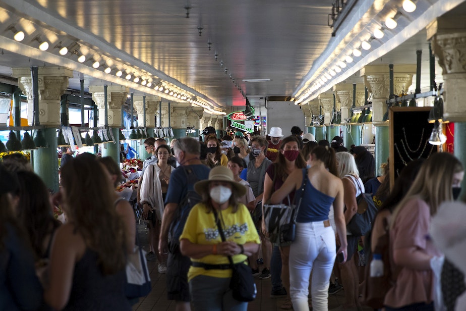 caption: Crowds of people make their way through Pike Place Market on Wednesday, August 11, 2021, in Seattle.