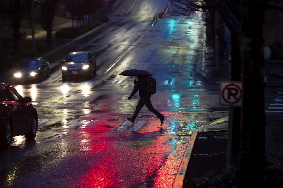 caption: A pedestrian crosses Denny Way with an umbrella early in the morning on Tuesday, February 25, 2025, in Seattle's South Lake Union neighborhood.